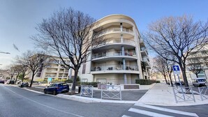 A multi-story residential building with balconies, a pedestrian crossing, and parked cars. - Terrace Apartment Near the Beach (Cagnes-sur-Mer)