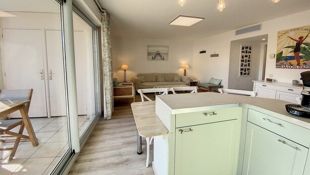 A modern kitchen with a dining area, a sofa, and a dining table. - Terrace Apartment Near the Beach (Cagnes-sur-Mer)