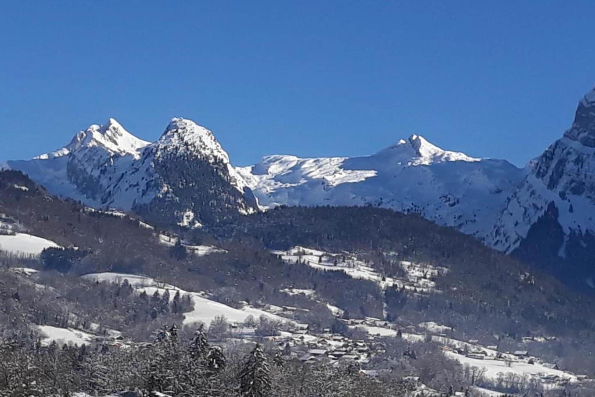 A mountainous landscape with snow-covered peaks and a valley with scattered buildings.