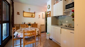 A compact kitchen with a dining table, chairs, a microwave, and a small refrigerator. - Apartment in Morillon at Ski Slope (Morillon)