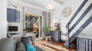 A modern living room with a sofa, TV, and dining area. - Garden Retreat Near the Beach (Agde)