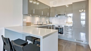 Una cocina moderna con una isla central, taburetes de bar y electrodomésticos de acero inoxidable.