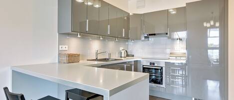 A modern kitchen with a central island, bar stools, and stainless steel appliances.