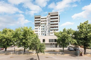 A multi-story residential building with balconies, a parking area, and trees in the foreground. - Hallera 165 by Downtown Apartments (Gdansk)