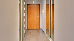 Un pasillo con una puerta de madera, un separador de vidrio e interruptor de luz en la pared.