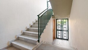 Una escalera con barandilla verde que lleva a una puerta con diseño de cuadrícula.
