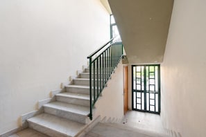 Eine Treppe mit grüner Geländer führt zu einer Tür mit Gittermuster.