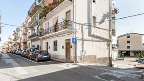 Una fila de coches estacionados a lo largo de una calle con edificios que tienen balcones y ventanas.