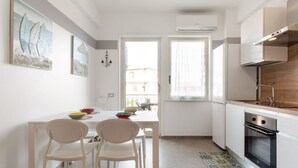 Una cocina moderna con armarios blancos, una mesa de comedor con sillas y obras de arte en las paredes.
