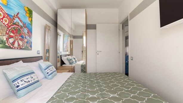 A bedroom with a bed, pillows, a painting, and a door.