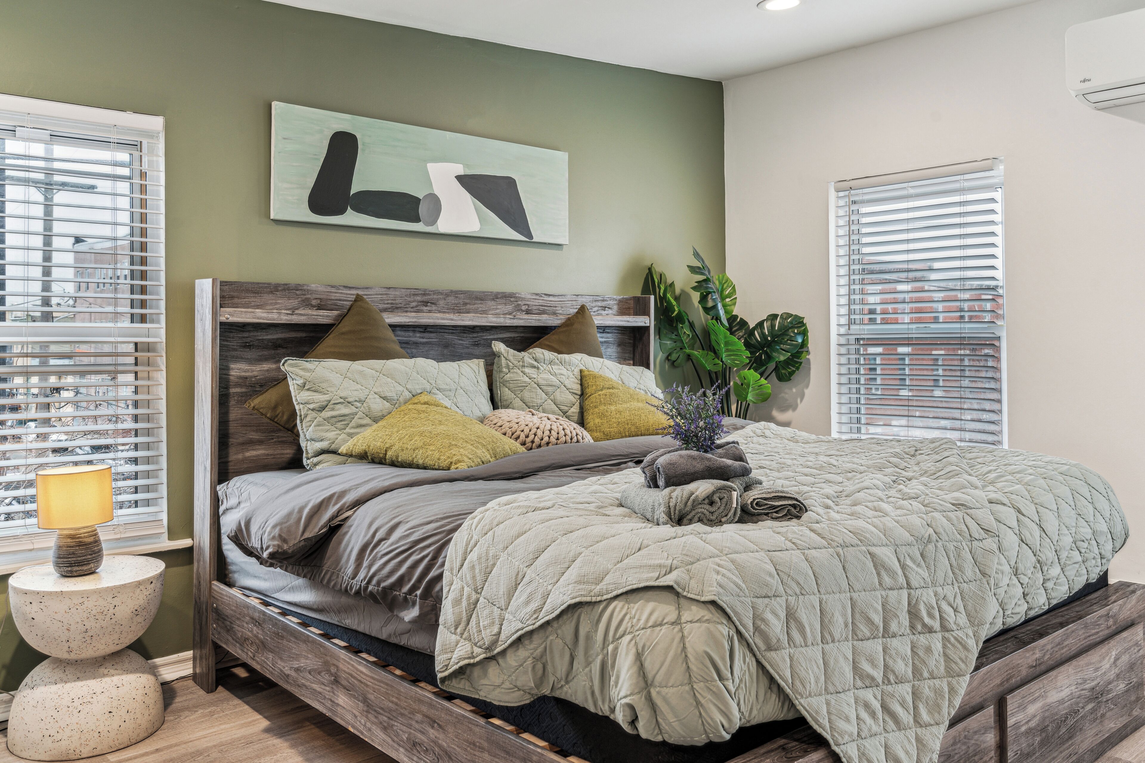 A bedroom with a bed, a bedside table, a lamp, and a wall-mounted artwork.