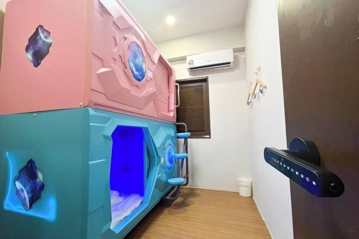A room with a large, colorful, futuristic-looking bed, a wall-mounted air conditioning unit, and a door with a modern lock system.