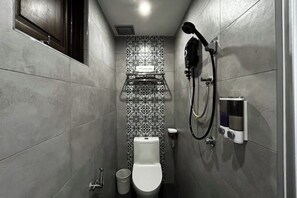 A narrow bathroom with a toilet, a shower, and a hand dryer. - mana mana hotel • Melaka • (Melaka)