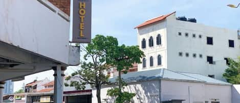 Hotel com placa, árvore e edifício com telhado vermelho.