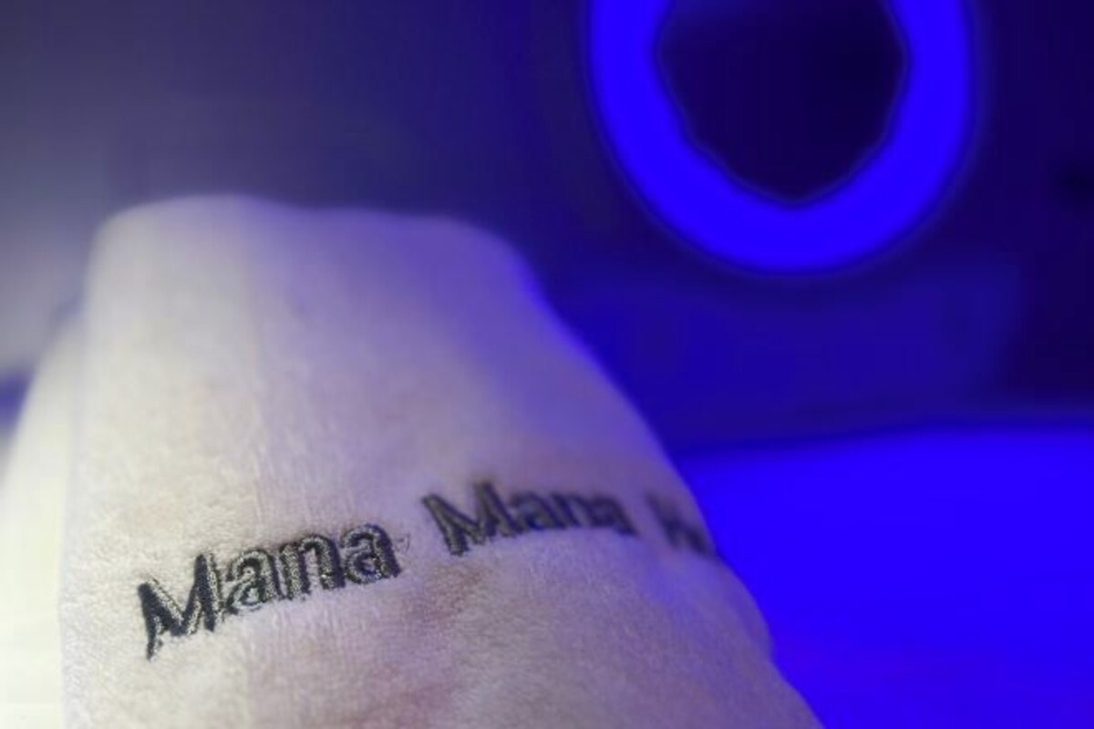 A close-up of a tattoo on a hand with the text 'Mana Mana.'