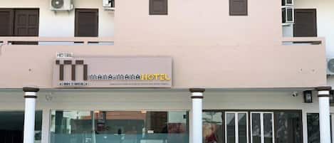 A hotel with a sign that reads 'MAMA-MAMA HOTEL' and a large glass entrance.