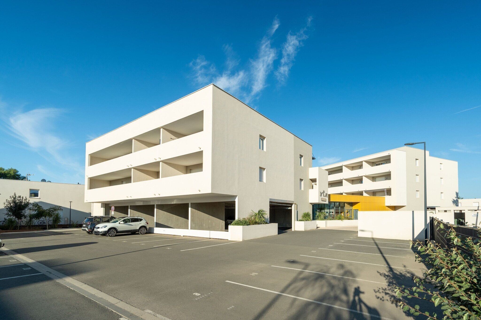 Un parking moderne à plusieurs étages, doté d’un design épuré et minimaliste.