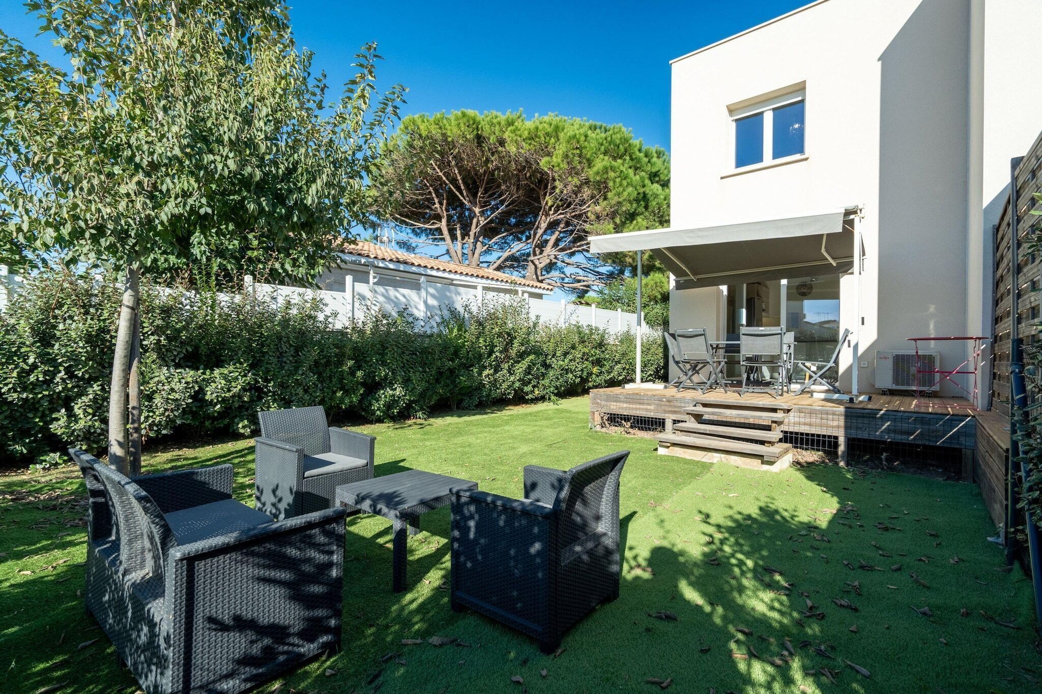 Een modern huis met een patio, meubilair buiten en een klein terras.