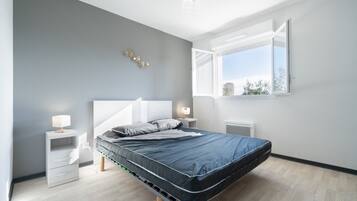 A modern bedroom with a bed, bedside tables, and a window.