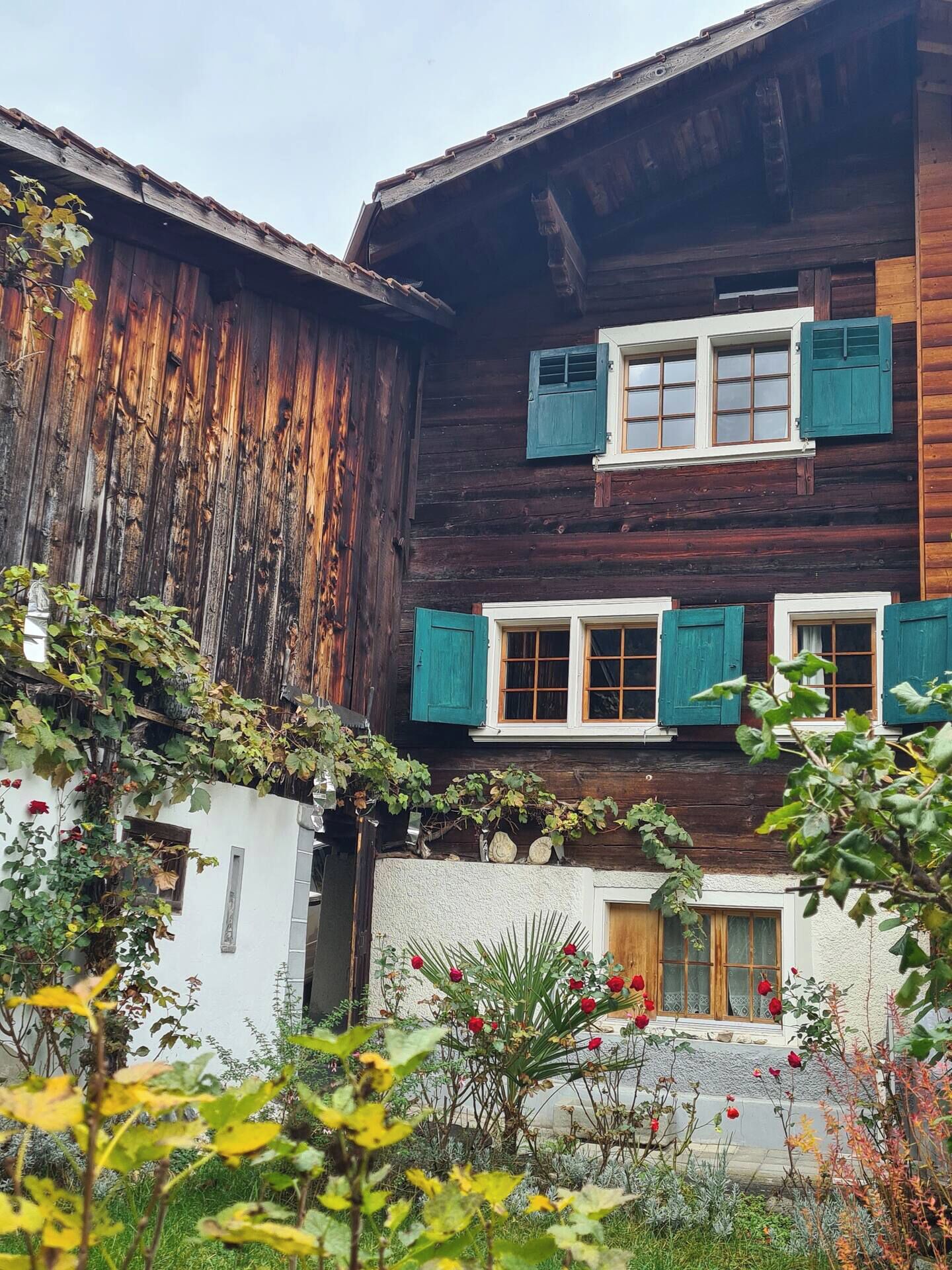 Une maison rustique en bois, dotée de fenêtres à deux étages et d’un mur extérieur blanc.