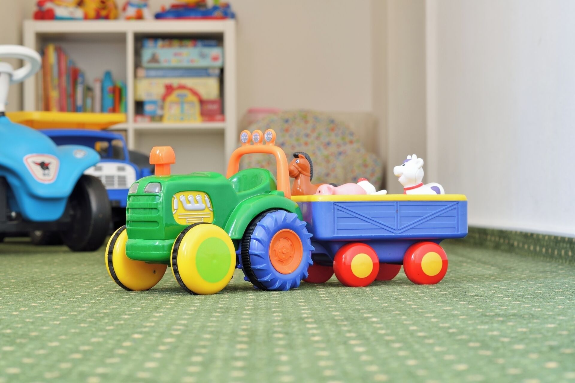 A toy tractor with a trailer carrying a pig and a cow.