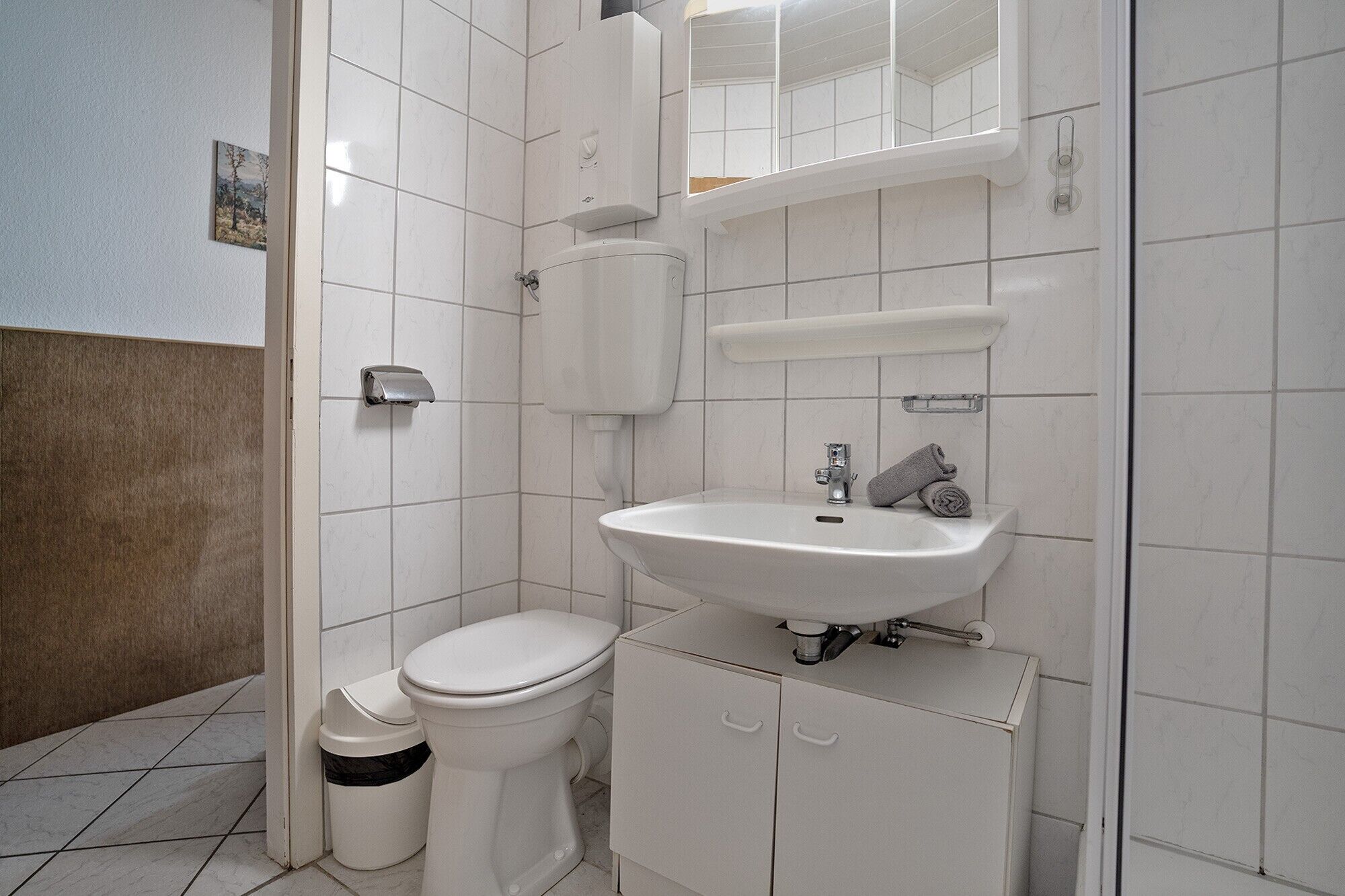 Ein Badezimmer mit Toilette, Waschbecken und Stauraumschrank.