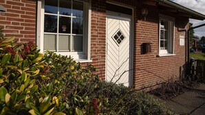 A brick building with a white door, windows, and a small porch area.