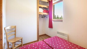 A small room with a single bed, a chair, a wooden wardrobe, and a window with a view of trees. - Cozy Ski Retreat in Chamrousse (Chamrousse)