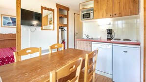 A compact kitchen with wooden cabinets, a microwave, a coffee maker, and a dishwasher. - Cozy Ski Retreat in Chamrousse (Chamrousse)