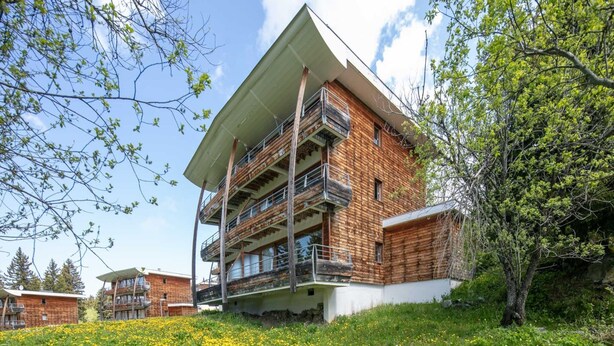 A multi-story building with a modern design, featuring balconies and a flat roof. - Cozy Ski Retreat in Chamrousse (Chamrousse)