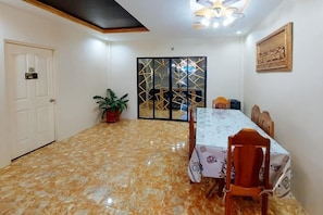 A dining area with a table and chairs, a potted plant, and a decorative screen. - RedDoorz @ R2K Pension House (Puerto Princesa)