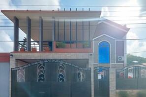 Um edifício residencial com uma porta de garagem em destaque, uma varanda e uma janela azul.