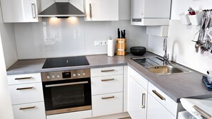 Een moderne keuken met witte kastjes, roestvrijstalen apparatuur en een inbouwoven.