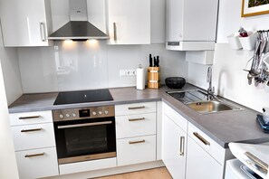 A modern kitchen with white cabinetry, stainless steel appliances, and a built-in oven.