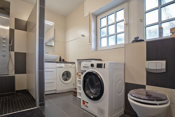 Un baño moderno con lavadora, inodoro y ducha.