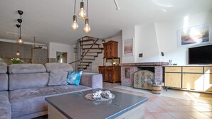 Een moderne woonkamer met een bank, salontafel, open haard en een trap.