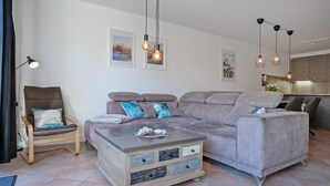 Een moderne woonkamer met een bank, fauteuil, salontafel en hanglampen.