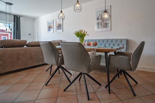 Un comedor con mesa, sillas, un sofá e iluminación colgante.