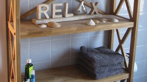 Ein Holzregal mit einem Segelbootsmodell, einem Buch mit dem Titel 'Wohnwie am Meer' und dem Wort 'RELAX' in der mittleren Ablagefläche.