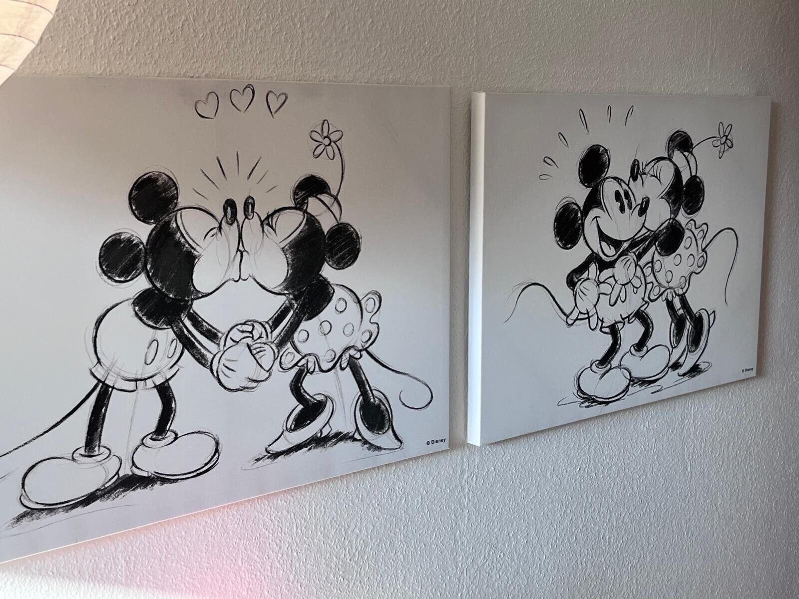 Two black and white Mickey Mouse paintings on a wall.