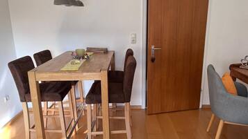 A dining area with a wooden table, six chairs, a small side table, and a door.