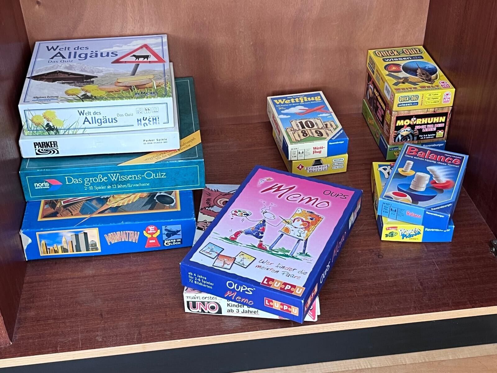 A collection of board games in a wooden cabinet.
