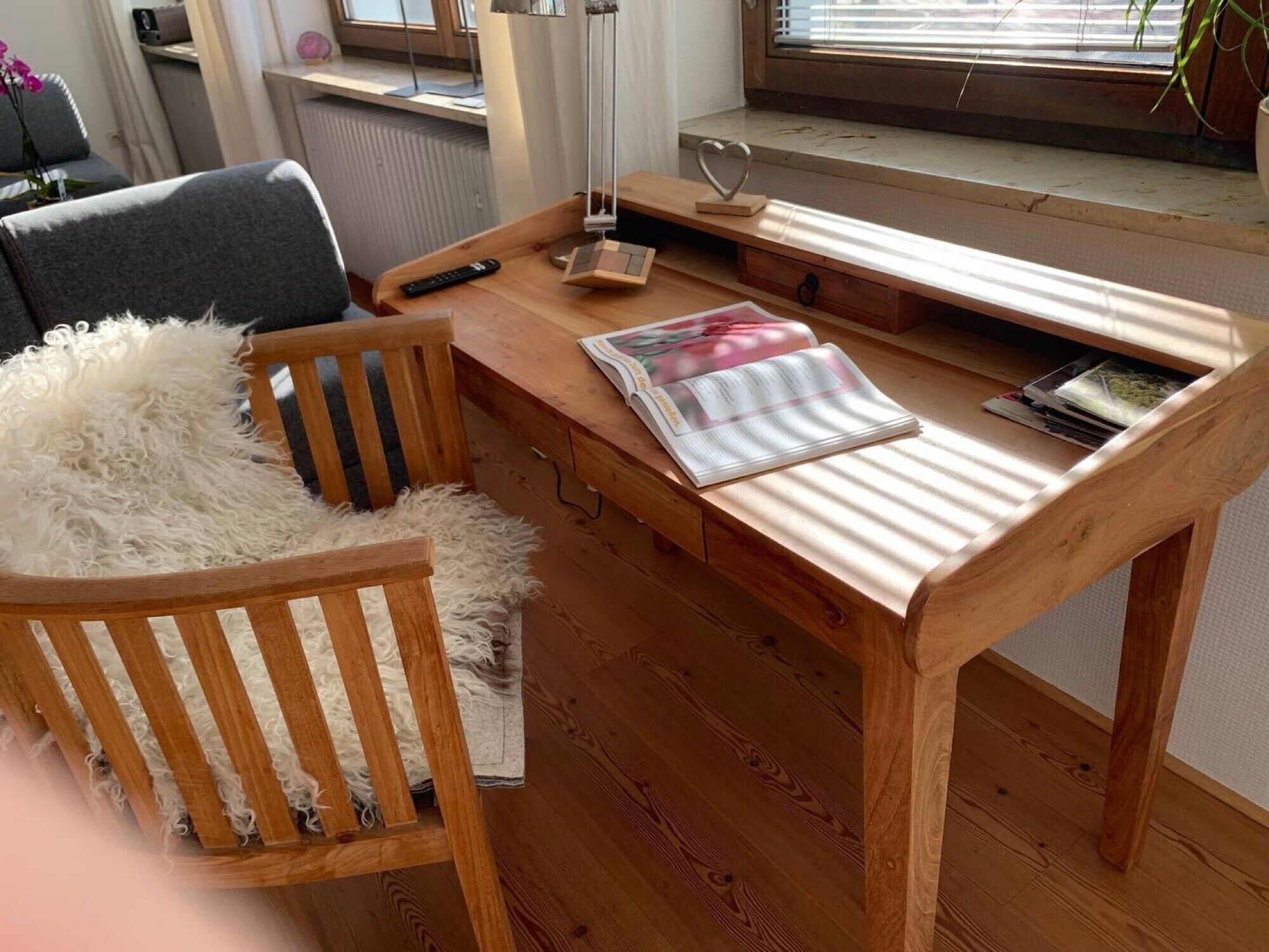 A wooden desk with a chair, a lamp, and a heart-shaped decoration.