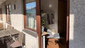 Ein Zimmer mit Holztisch, Stühlen, einem Bücherregal und einem Fenster mit Aussicht.