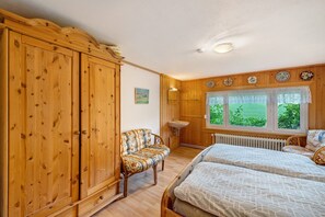 Ein Schlafzimmer mit Holzkämnern, einem Bett, einem Schlafsofa, einem Kleiderschrank, einem Fenster mit Aussicht und einer Heizung.