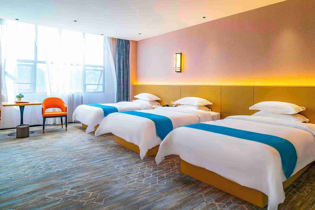 A hotel room with two beds, a small table, a chair, and a nightstand.