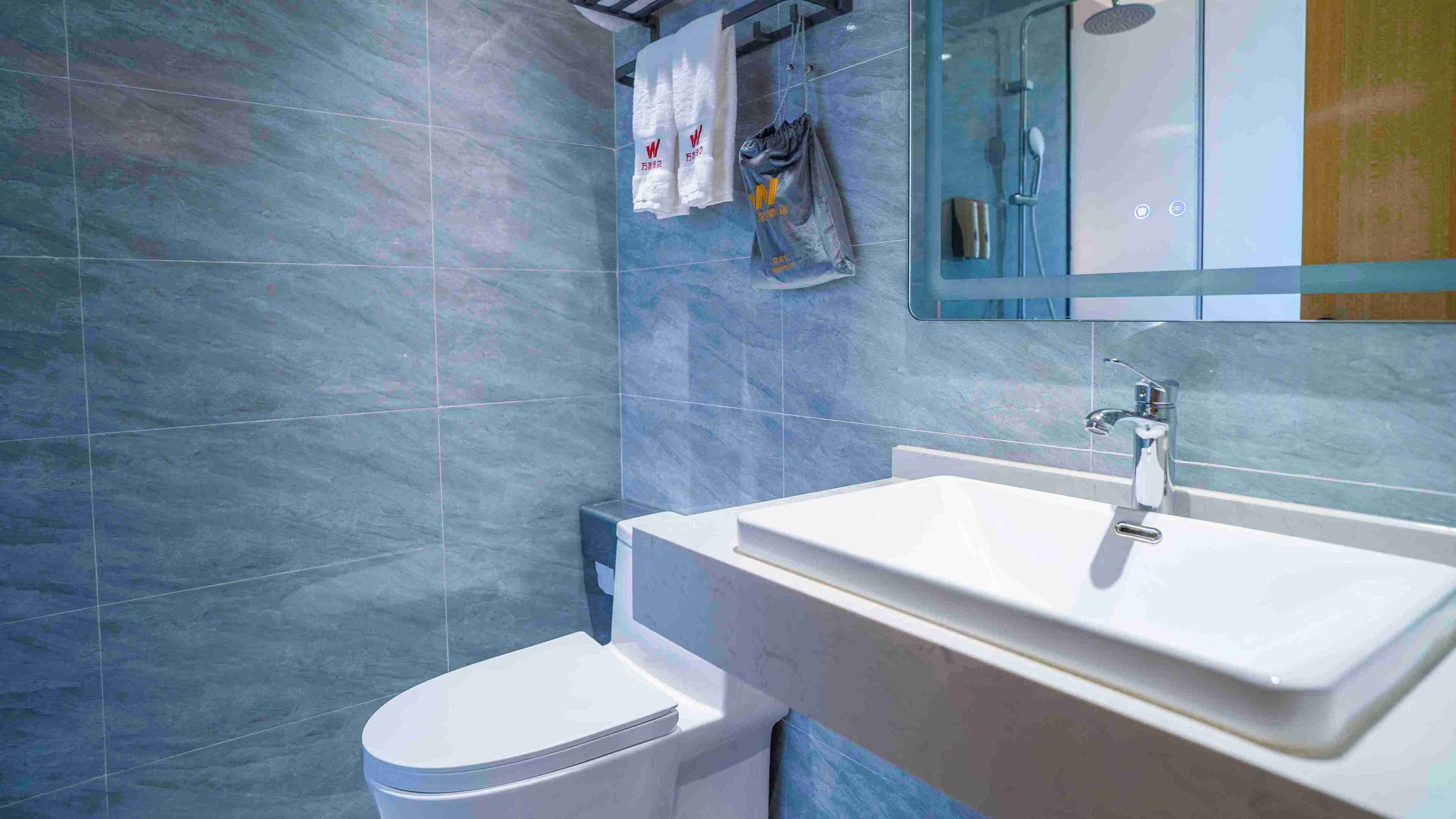 A modern bathroom with a white sink, a toilet, and a shower area.