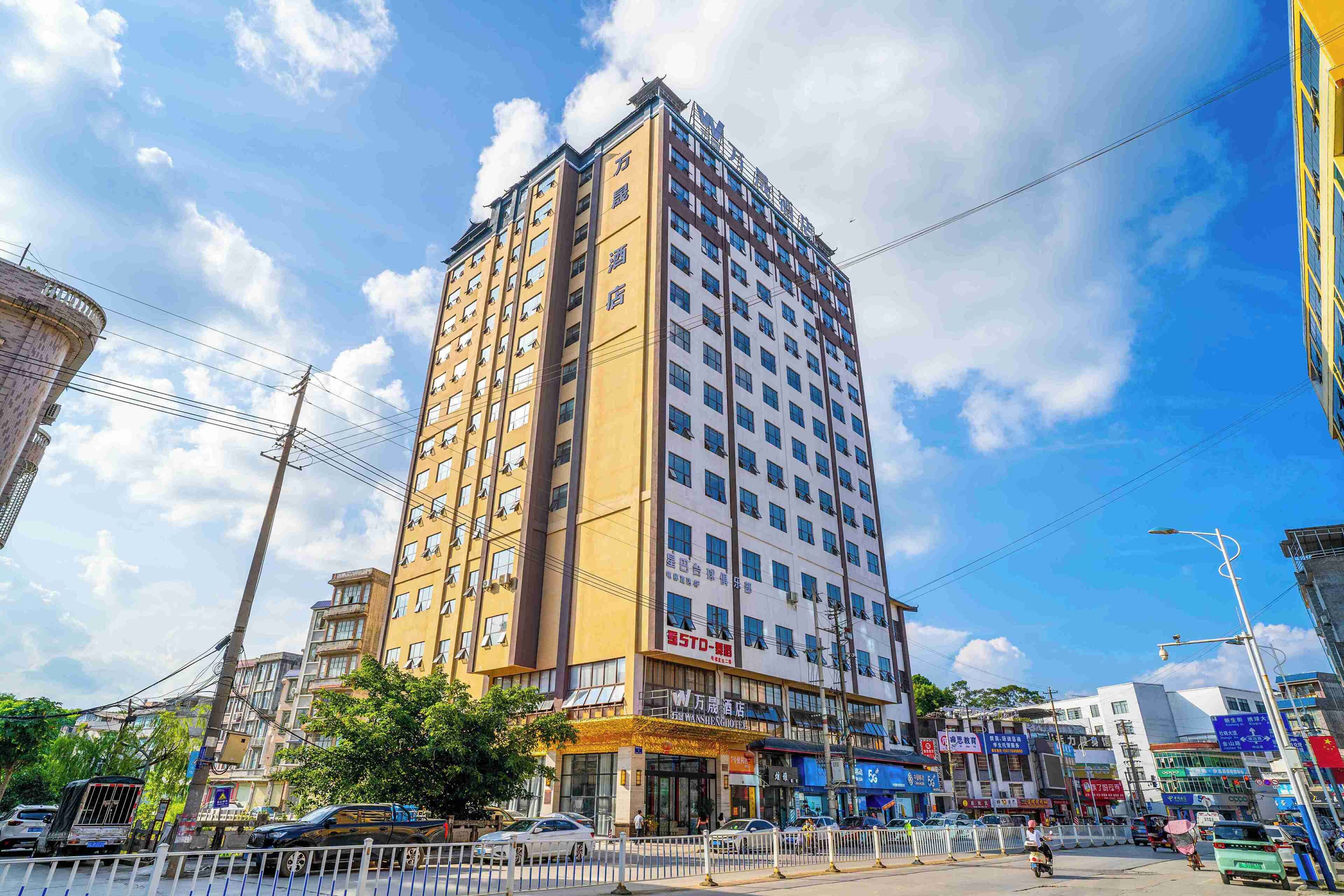 A multi-story hotel with a yellow facade, multiple windows, and a visible entrance with signage.