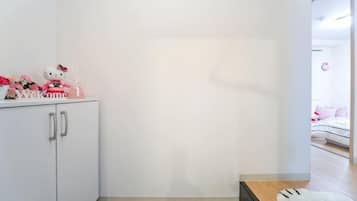 A room with a white wardrobe, a small table, and a bed with pink bedding.