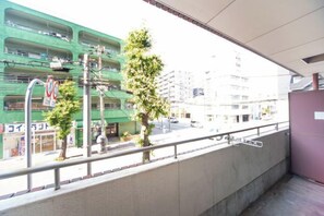 A balcony with a view of a city street, a green building, and a tree. - 2 bed room near Osaka Castle.#202 (Osaka)